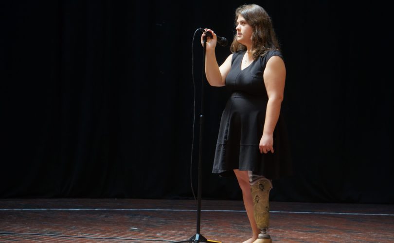 Sophia standing in front of a microphone on stage, ready to sing