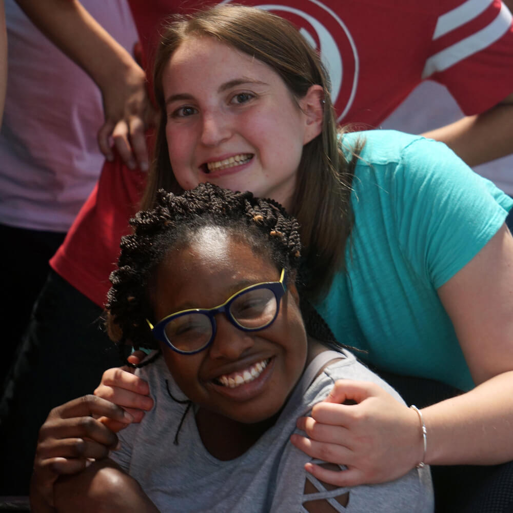 Two friends smiling, hugging and posing for the camera