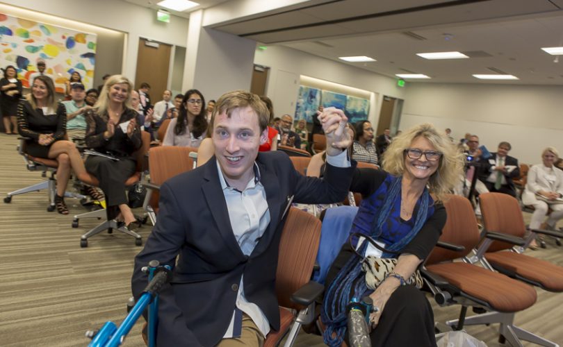 Austin sitting in the front of the room at Party for PYD alongside Regina Snowden, PYD's executive director.