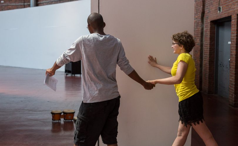 Young man holds a young woman's hand while walking onto a stage
