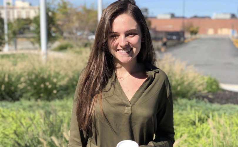 Nicole standing in front of the PYD office, holding a coffee