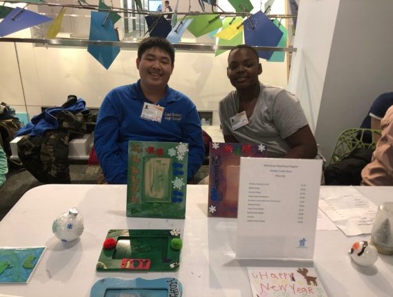 Two Career Readiness students smile sitting down at a table with Christmas frames and ornaments