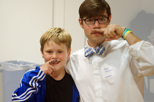Brody (left) and Mike (right) stand side by side with drawn on mustaches.
