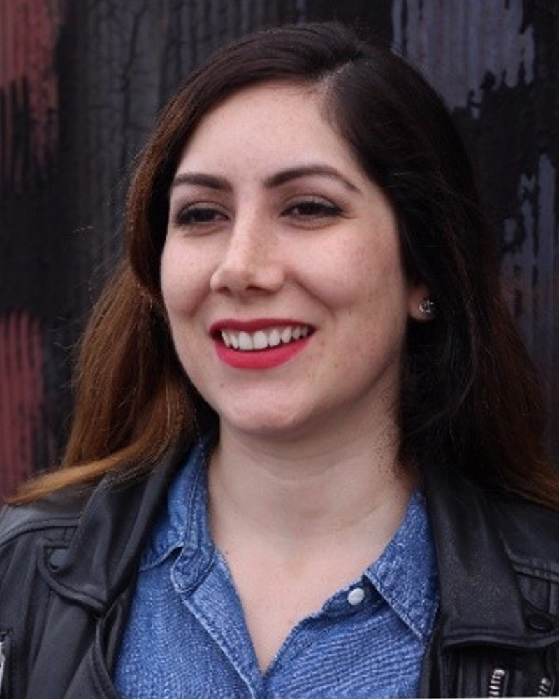 Fair skinned hispanic woman smiling wearing red lipstick.