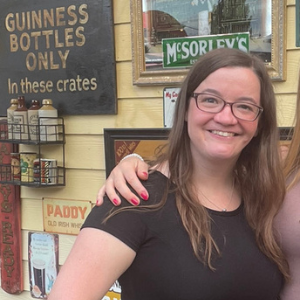 Woman smiling while wearing black dress and black glasses