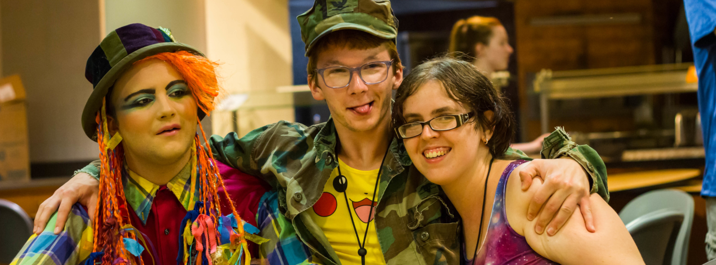 Three queer young adults with disabilities hugging each other while laughing at the camera