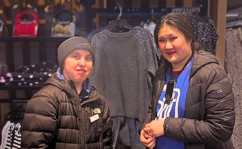 A mentor and mentee are standing next to each other at a clothing display at Macy's.