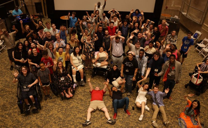 YLF participants pose for the camera, all in different poses, including lying on the ground, putting peace signs, or arms up.